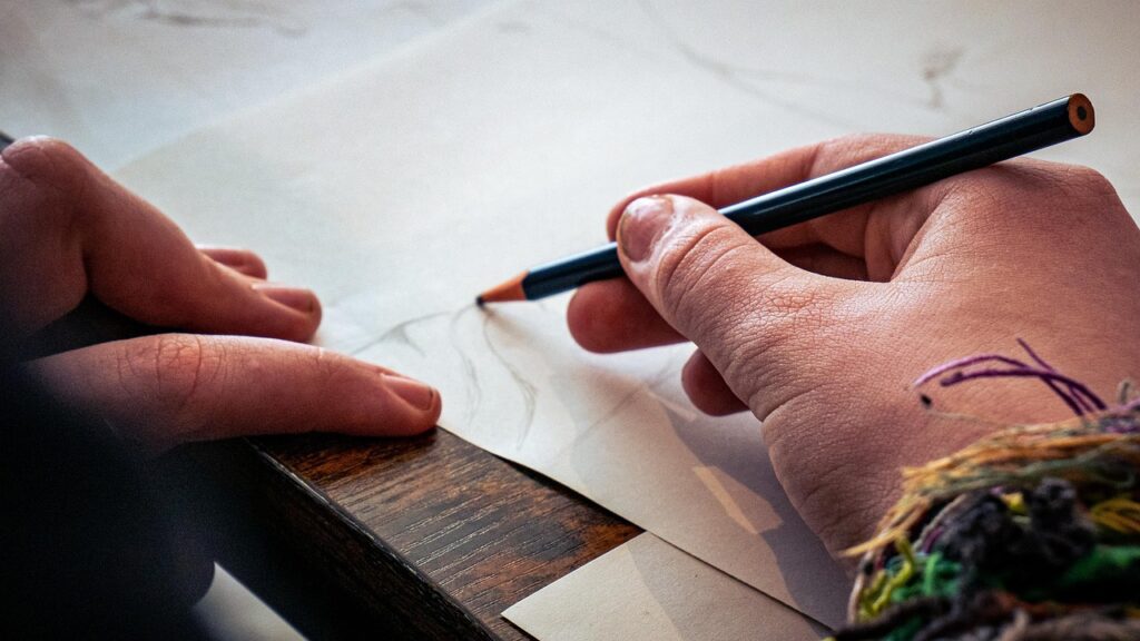 Un par de manos dibujando un boceto  con lápiz sobre papel.